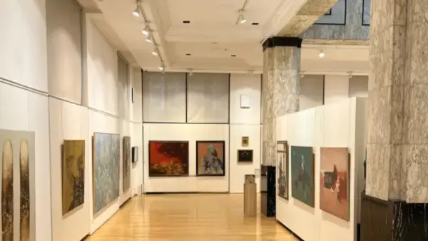 Унутрашњост музеја са белим зидовима и дрвеним подом, са изложеним сликама и скулптуром