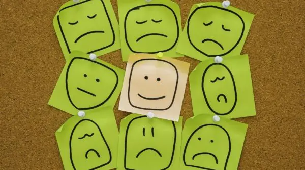 Папирићи на мемо табли, на једном, у средини, је нацртан срећан смајли, а око њега више тужних